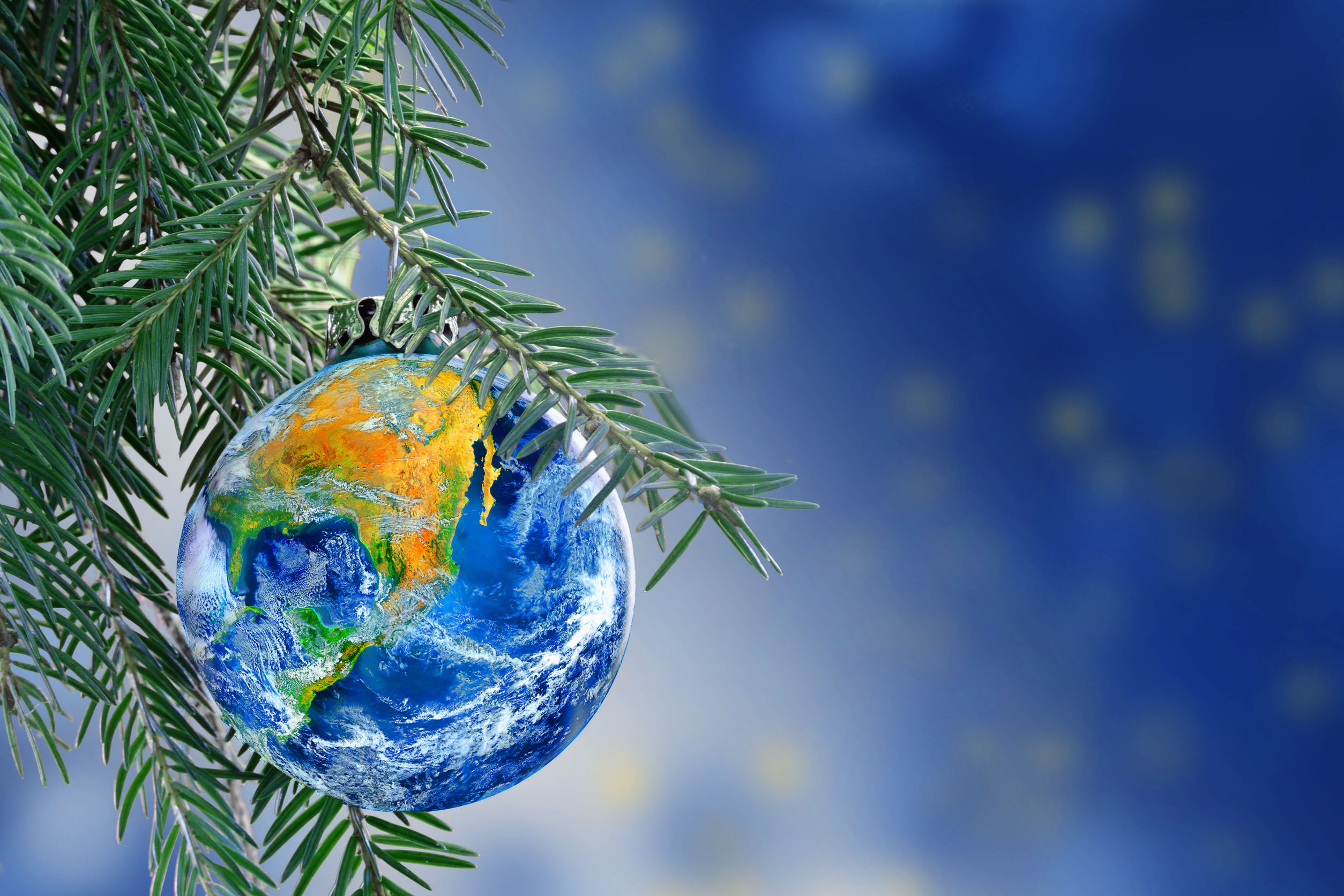earth globe as a Christmas bauble on fir branch of a christmas tree, Merry Christmas all over the world, copy space